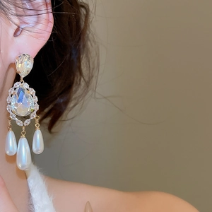Close-up of elegant gold-plated drop earrings with crystals and pearls on model