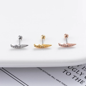 Macro shot of three dagger-shaped ear studs in silver, gold and rose gold with tiny zircons
