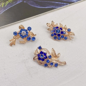 Macro shot of vintage style alloy flower brooches with blue rhinestones and gold hollow base