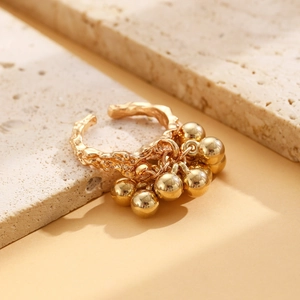 Detailed shot of textured gold open ring with bead pendants on rustic stone background