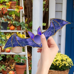 Detail of purple marble bat ornament with gold trim held in an autumn garden
