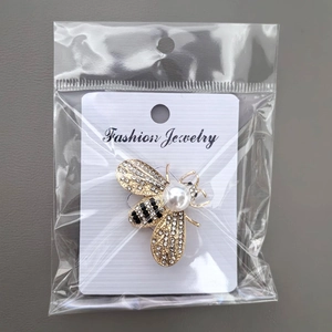 Detailed view of bee brooch with pearls and rhinestones in clear retail packaging
