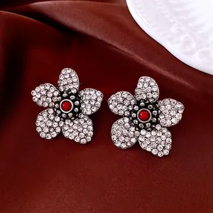Macro detail of vintage floral earrings with red beads and crystals on brown silk