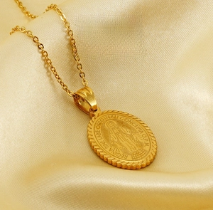 Detailed macro view of a gold stainless steel Virgin Mary oval pendant on silk