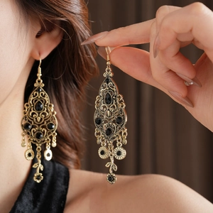 Close-up of vintage golden filigree drop earrings with black stones on a model