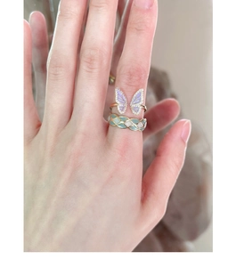 Close-up of golden butterfly ring with purple enamel and woven ring with green enamel
