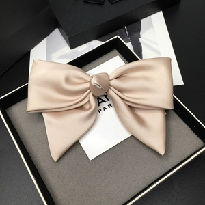 Detailed view of a champagne satin bow hair clip inside an elegant gift box