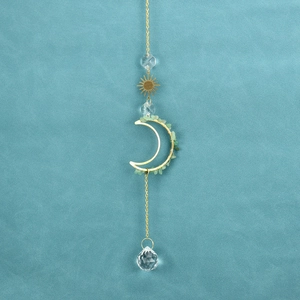 Detail of sun and moon crystal suncatcher with green stones and polished metal chains