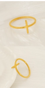 Close-up of minimalist gold cross ring on white velvet and ceramic background