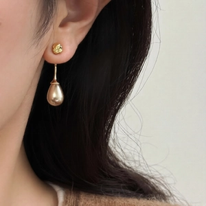 Elegant gold teardrop earrings with organic lava texture shown on female model