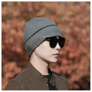 Detail shot of mid-grey knit beanie with black stripe trim in a cozy autumn setting