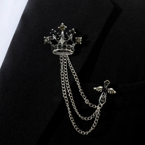 Détail d'une épingle de col couronne argentée avec croix d'aigle et chaîne sur blazer noir