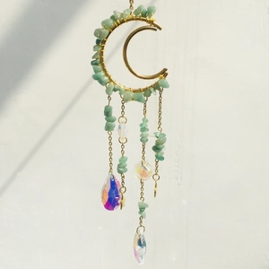 Macro shot of golden crescent moon pendant with green natural amethyst crushed stones