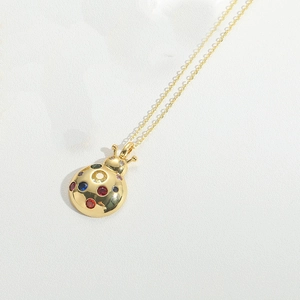 Macro shot of gold-plated mushroom pendant necklace with colorful inlaid crystals
