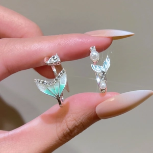 Detailed view of mermaid tail rings featuring green enamel, white pearls and zircons
