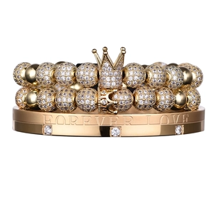Detailed view of golden bracelet set featuring crown charms and Forever Love engraving