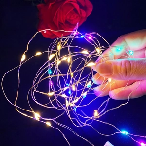 Macro detail of hand holding flexible LED copper wire lights with a red rose decor
