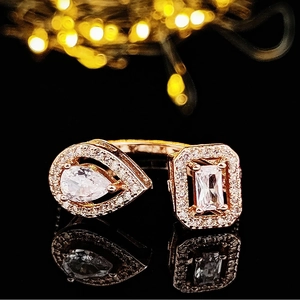 Detail eines Roségold-Rings mit Tropfen- und Rechteckkristallen auf schwarzer Reflexfläche