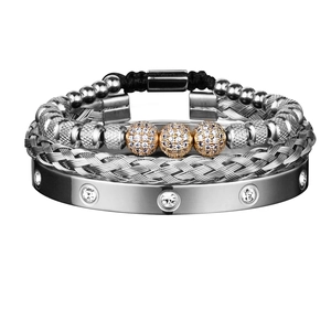 Close-up of a three-piece jewelry set featuring silver mesh and gold crystal-set bracelets