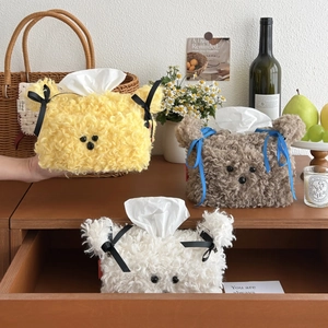 Three plush bear tissue box covers in brown, white and yellow on a wooden desk