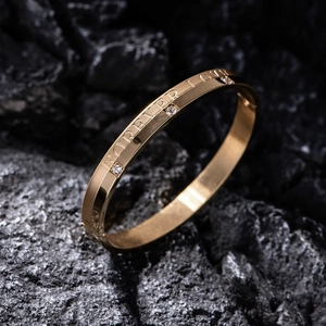 Macro shot of gold-plated forever love bracelet with diamonds on black rock background