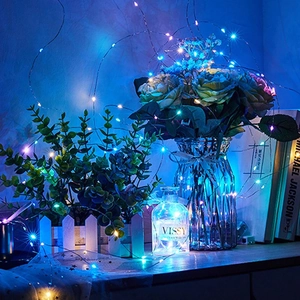 Detail of colorful LED copper wire string lights inside a decorative glass flower vase