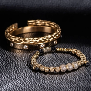 Detail view of a gold braided bangle and a black corded beaded bracelet with clear gemstones