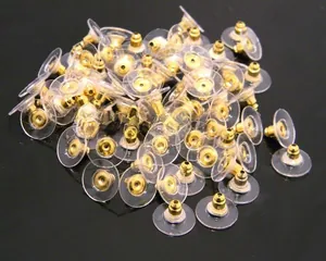 Close-up of golden metal earring backs with transparent plastic discs in bulk