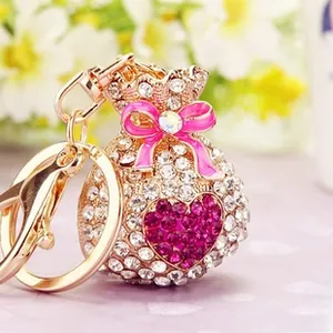 Detailed macro of gold money bag keychain with pink rhinestones and a bow heart