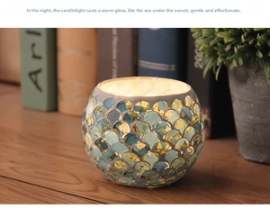 Macro shot of mosaic glass candle holder with glowing blue and green fish scale pattern
