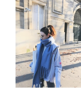 Detail of blue knitted mohair scarf with tassels paired with a casual grey hoodie