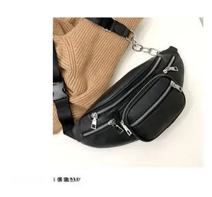 Close-up of black PU leather waist bag with silver chains and multiple zippers