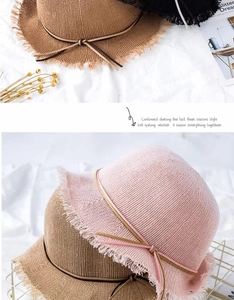 Detailed weave of a summer straw hat featuring raw fringe edges and a delicate leather bow