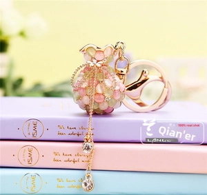 Détail d'un porte-clés sac de fortune avec pierres œil de chat roses sur des livres
