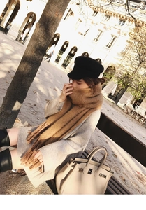 Close-up of camel mohair scarf with tassels paired with a grey knit dress and boots