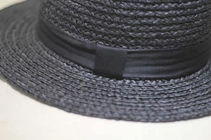 Close-up of black raffia straw hat detailing woven texture and stylish ribbon band