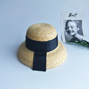 Detailed weave texture of summer straw sun hat with elegant black ribbon bow accent