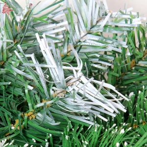 Close-up of artificial PVC Christmas branch with green needles and white snow spray details