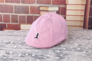 Close-up of pink striped kids beret featuring a black rabbit embroidery on a rustic background