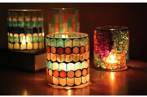 Macro detail of handmade mosaic glass candle holders with warm candle glow on a wooden table