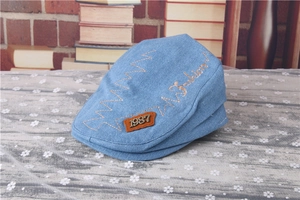Detail of blue denim baby beret with yellow fashion embroidery and vintage 1987 metal tag