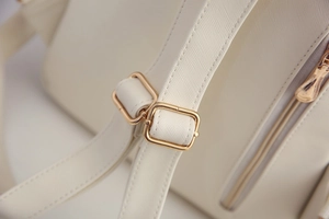 Detail des verstellbaren PU-Ledergurts mit goldener Metallschnalle am beigen Rucksack