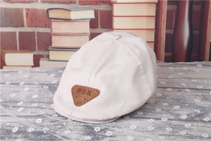 Close-up of white baby beret with brown leather WBK patch on a vintage background