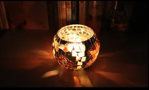 Macro detail of mosaic glass candle holder with warm geometric orange light patterns