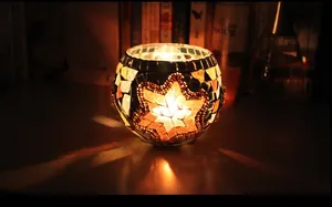 Detailed view of mosaic glass candle holder with star pattern and warm flickering flame