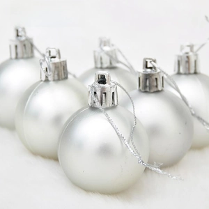 Detail of silver matte Christmas baubles with hanging strings on white plush background