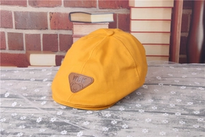 Detail of yellow kids beret featuring a sewn brown leather WBK bear patch