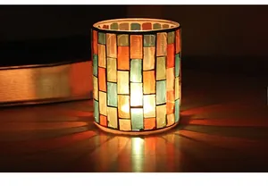 Detail of mosaic glass candle holder with warm light through colorful glass tiles
