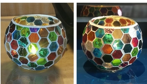 Detail of mosaic glass candle holder showing colorful reflections in candlelight