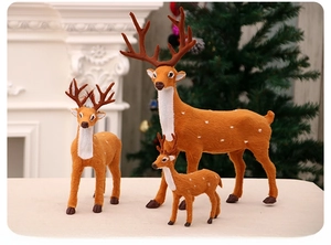 Three sizes of artificial Christmas reindeer statues in a cozy holiday fireplace setting